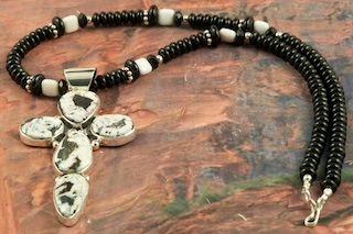 Stunning Cross Pendant featuring Genuine White Buffalo Turquoise set in Sterling Silver. The Cross Pendant is on a Genuine Black Onyx Necklace with Sterling Silver Beads and Clasp. This Beautiful Stone is formed from the minerals Calcite and Iron. It is mined near Tonopah Nevada. Created by Navajo Artist Evelyn Yazzie. Signed by the artist.